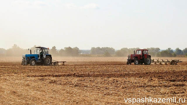 Трактора в поле производят вспашку земли